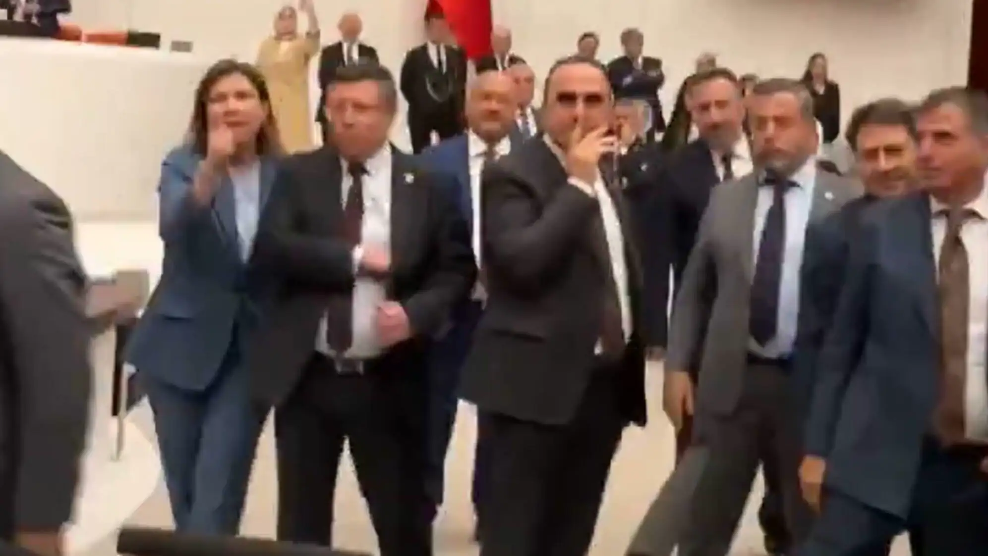 Meclisteki tartışmalar sırasında bir grup insan mikrofonların önünde duruyor.