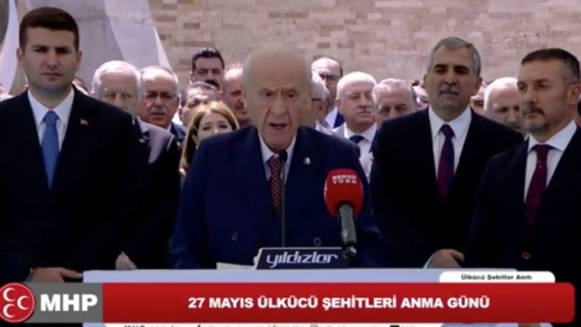 Devlet Bahçeli, kalabalık bir topluluğun önünde konuşma yapıyor. Devlet Bahçeli, kalabalık bir topluluğun önünde konuşma yapıyor.