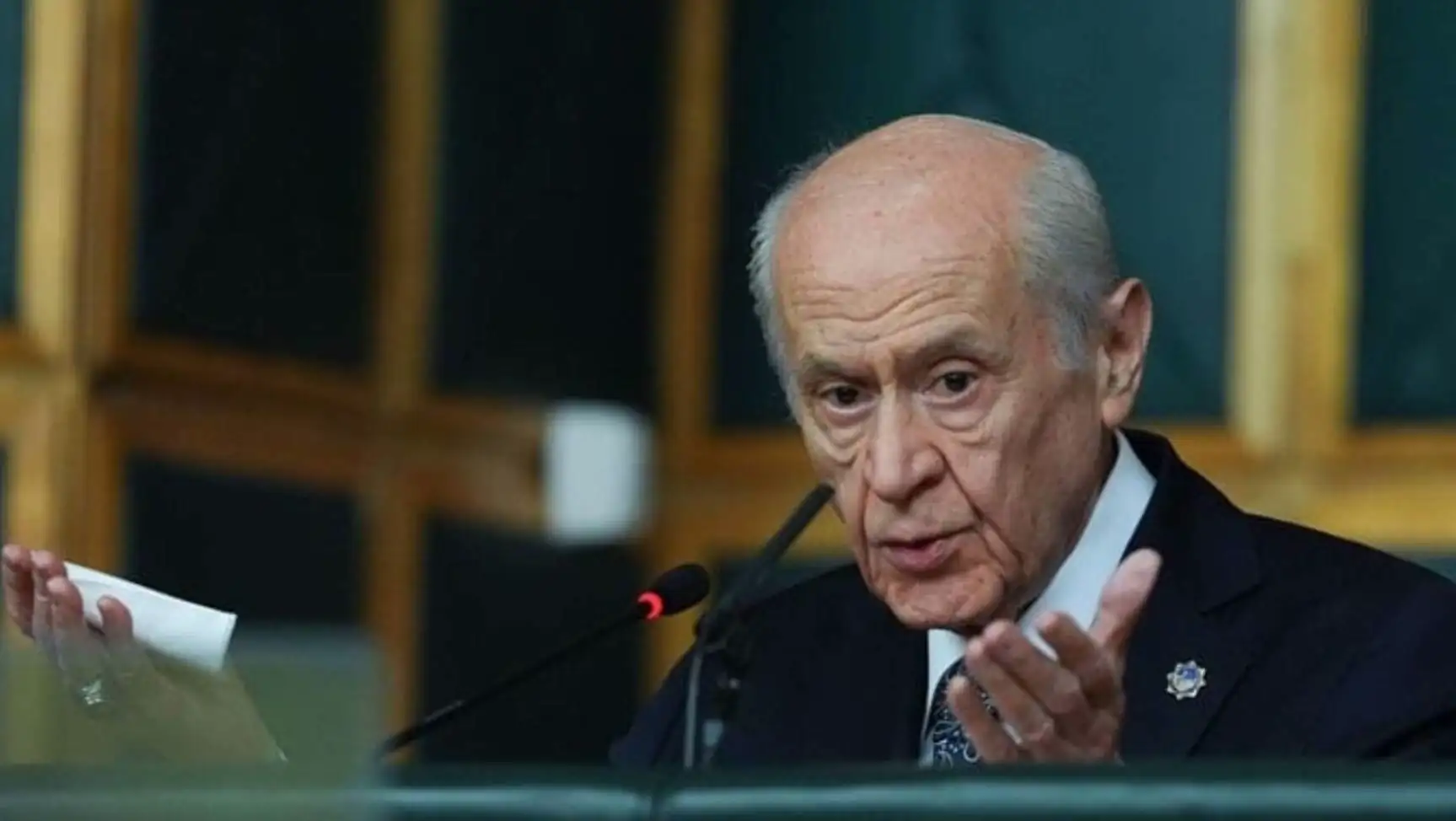Devlet Bahçeli speaking into a microphone.