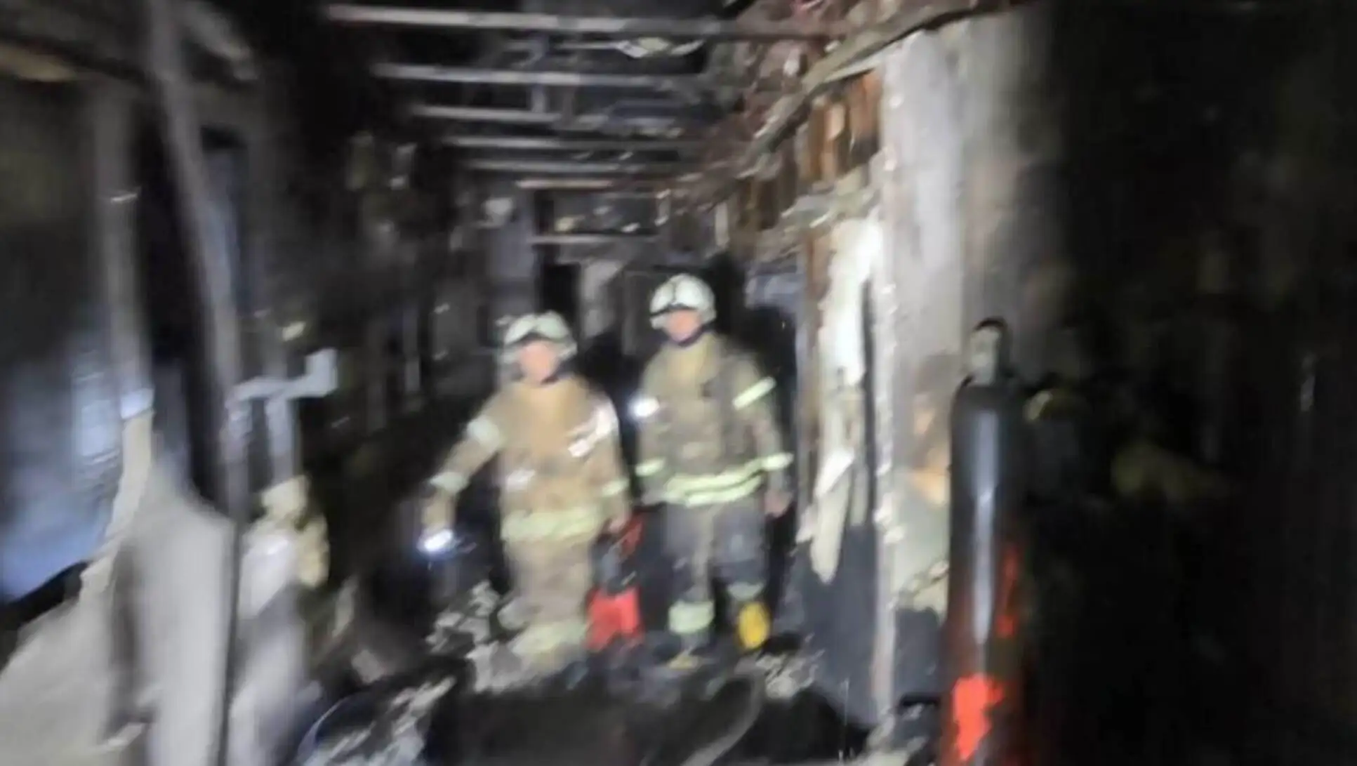 A blurry image of firefighters working in a dark room. A blurry image of firefighters working in a dark room.