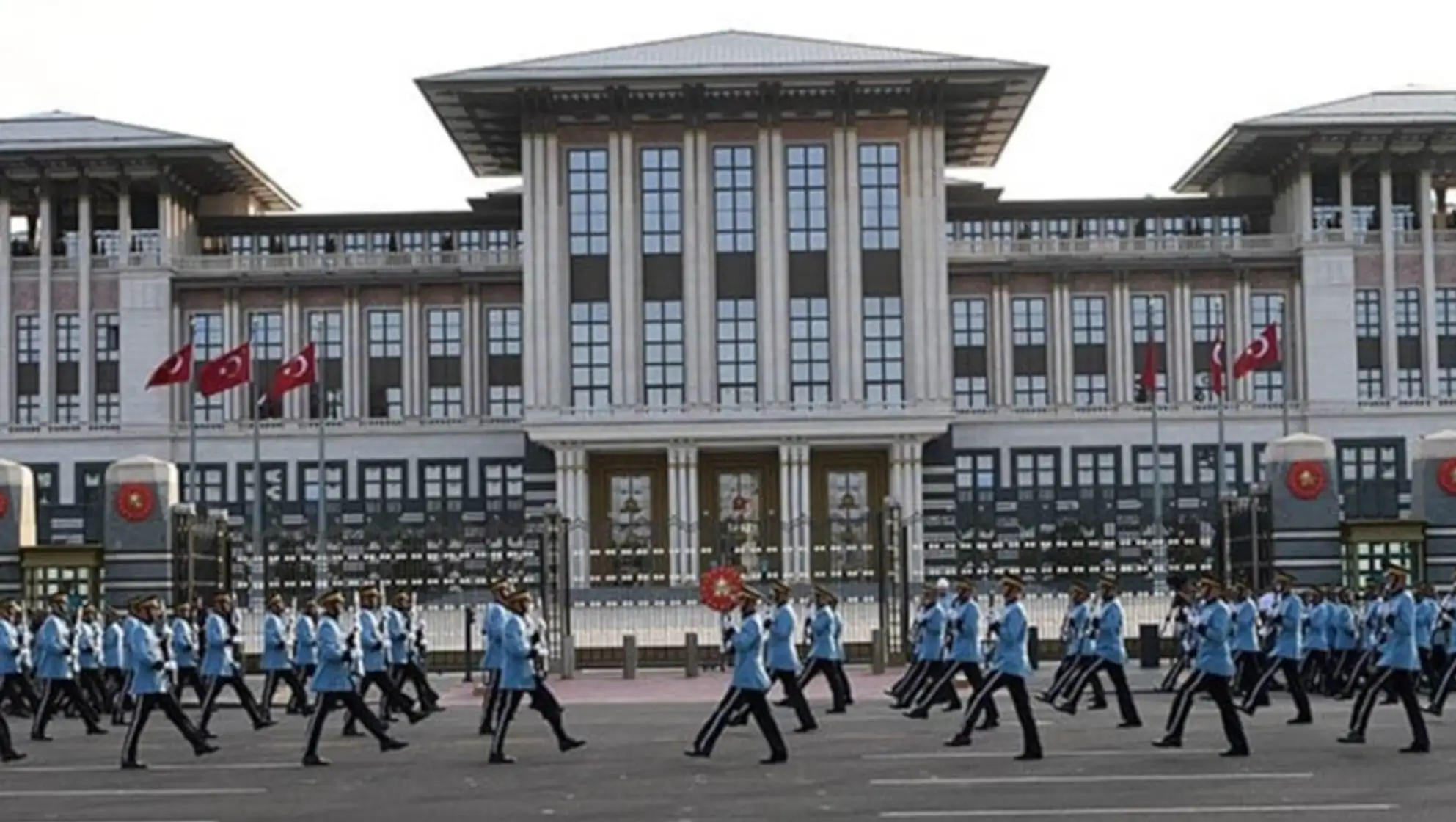 A group of people marching in front of a building. A group of people marching in front of a building.