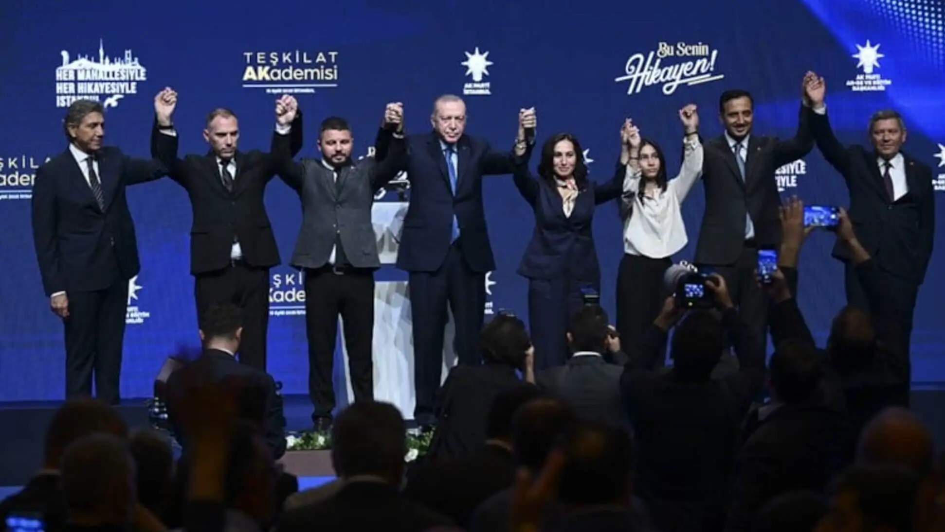Bir grup insan sahnede ellerini kaldırarak destek veriyor.