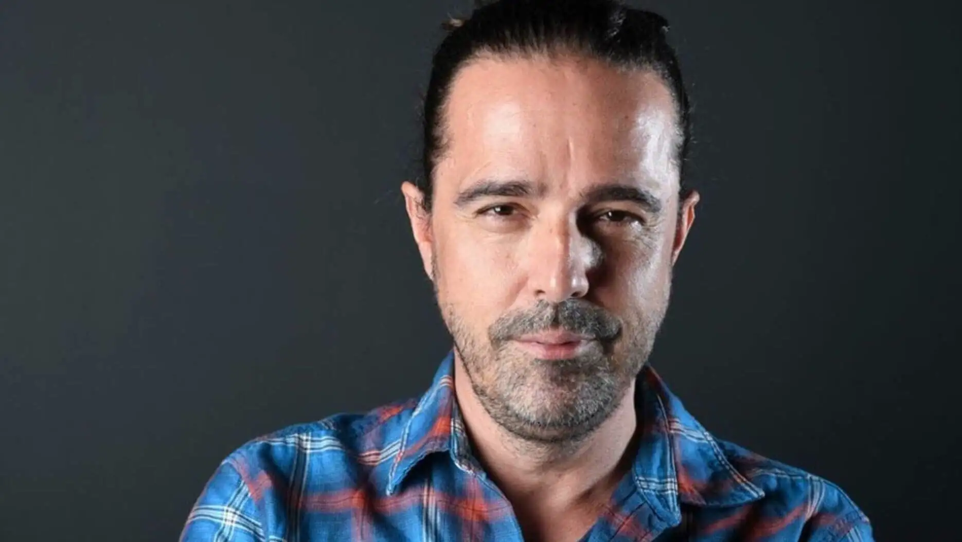 A man wearing a blue plaid shirt. A man wearing a blue plaid shirt.