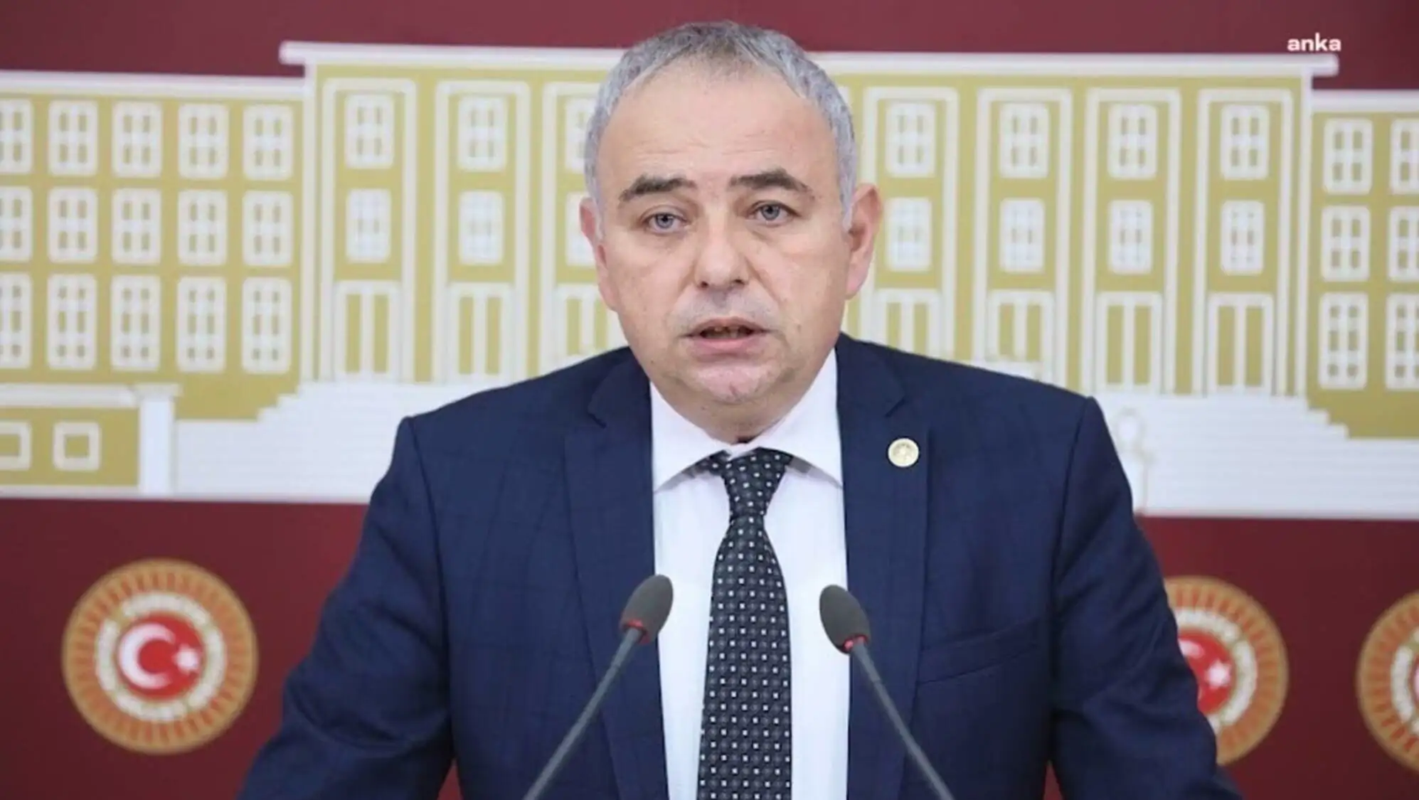 A man in a suit speaking into microphones. A man in a suit speaking into microphones.