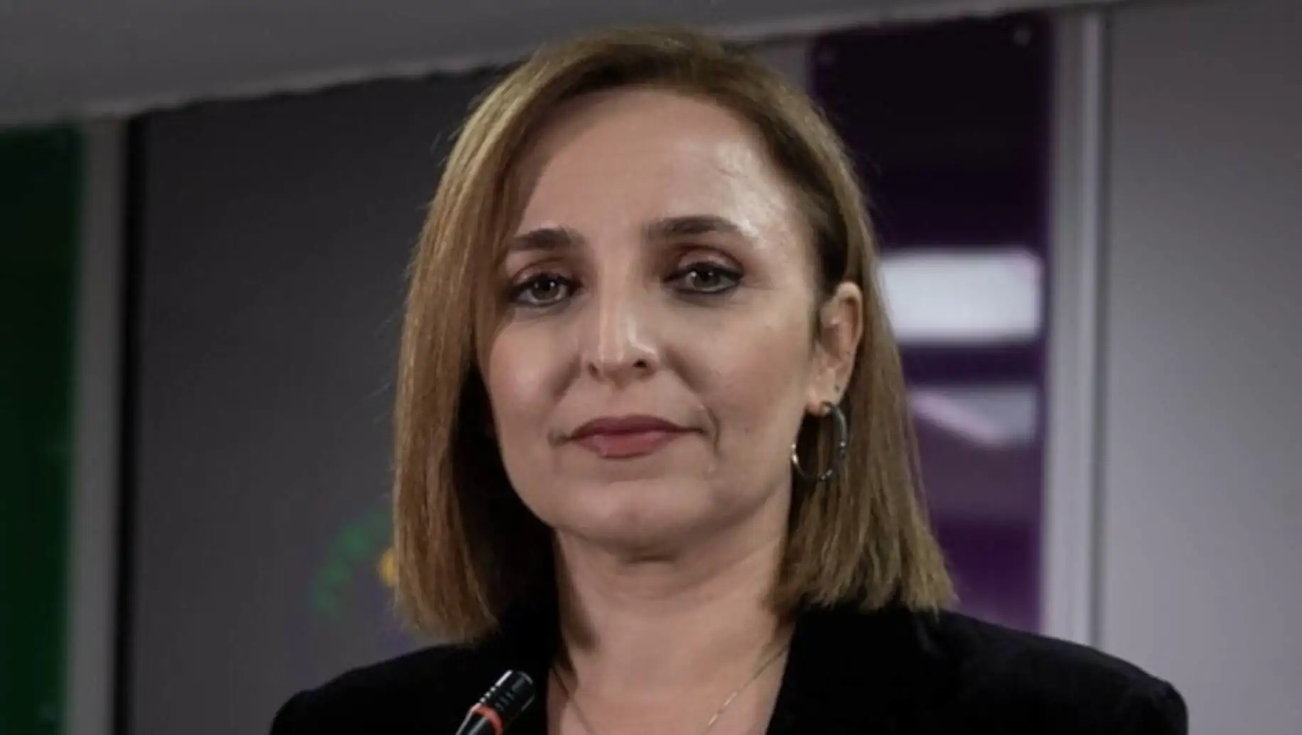 Kısa saçlı bir kadın, siyah ceket giymiş.