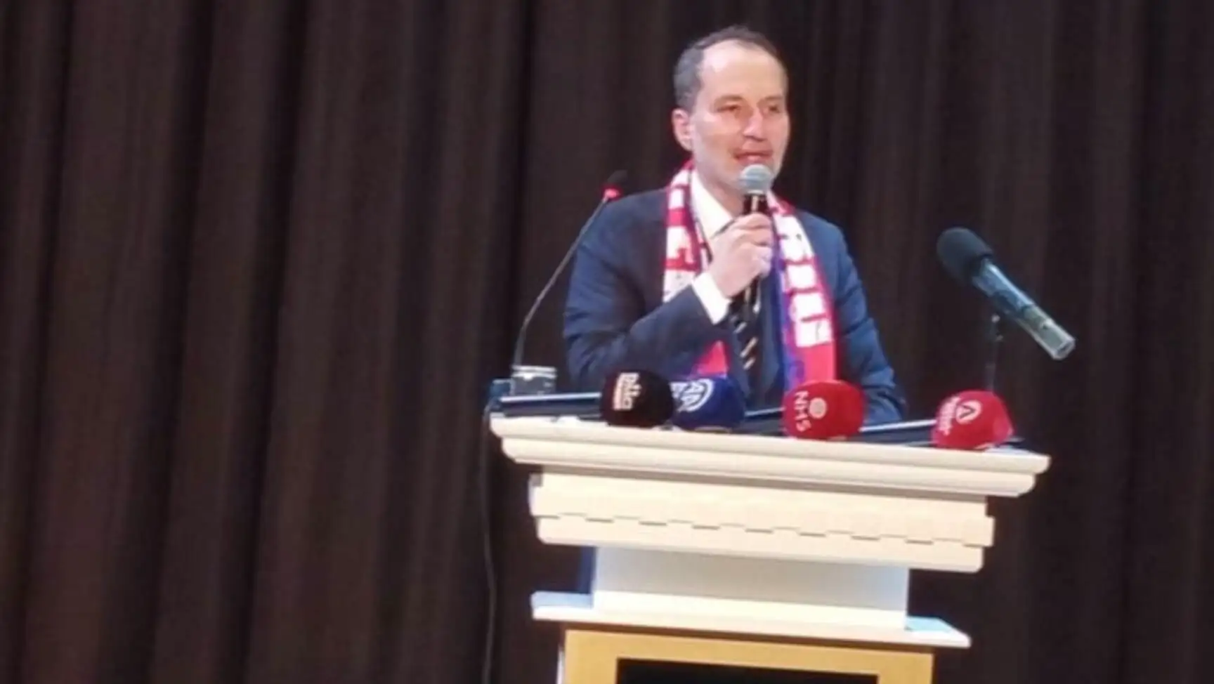 Fatih Erbakan bir podiumda mikrofonla konuşuyor. Fatih Erbakan bir podiumda mikrofonla konuşuyor.