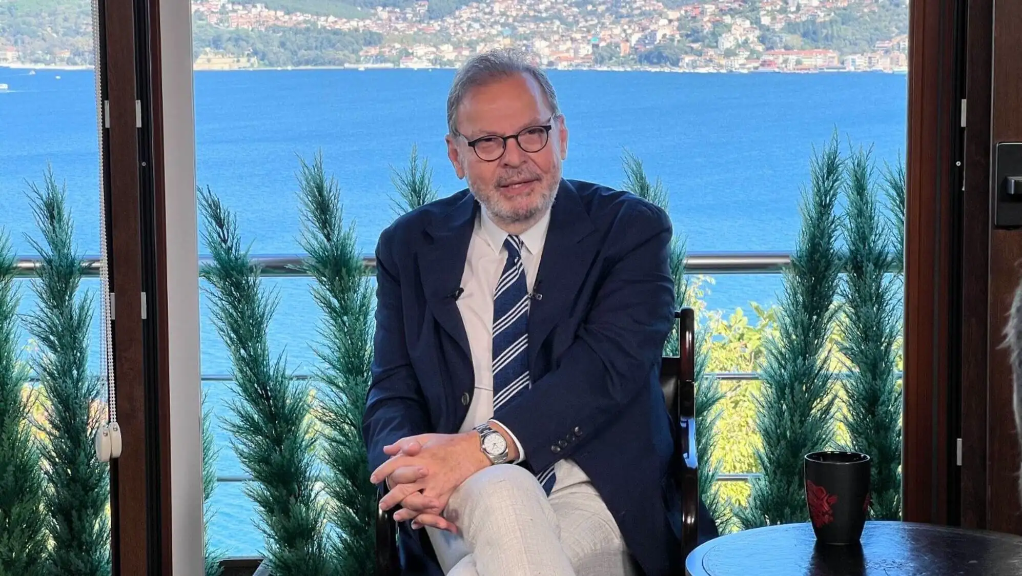 A man sitting in a chair with a view of water and land in the background. A man sitting in a chair with a view of water and land in the background.