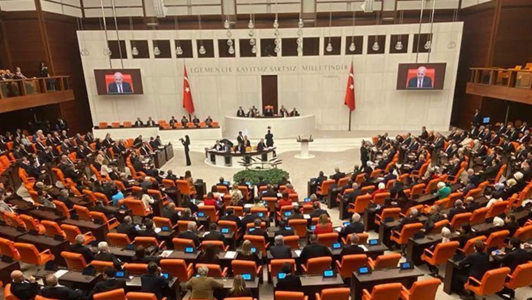 TBMM'de bir grup insan turuncu sandalyelerde oturuyor. TBMM'de bir grup insan turuncu sandalyelerde oturuyor.