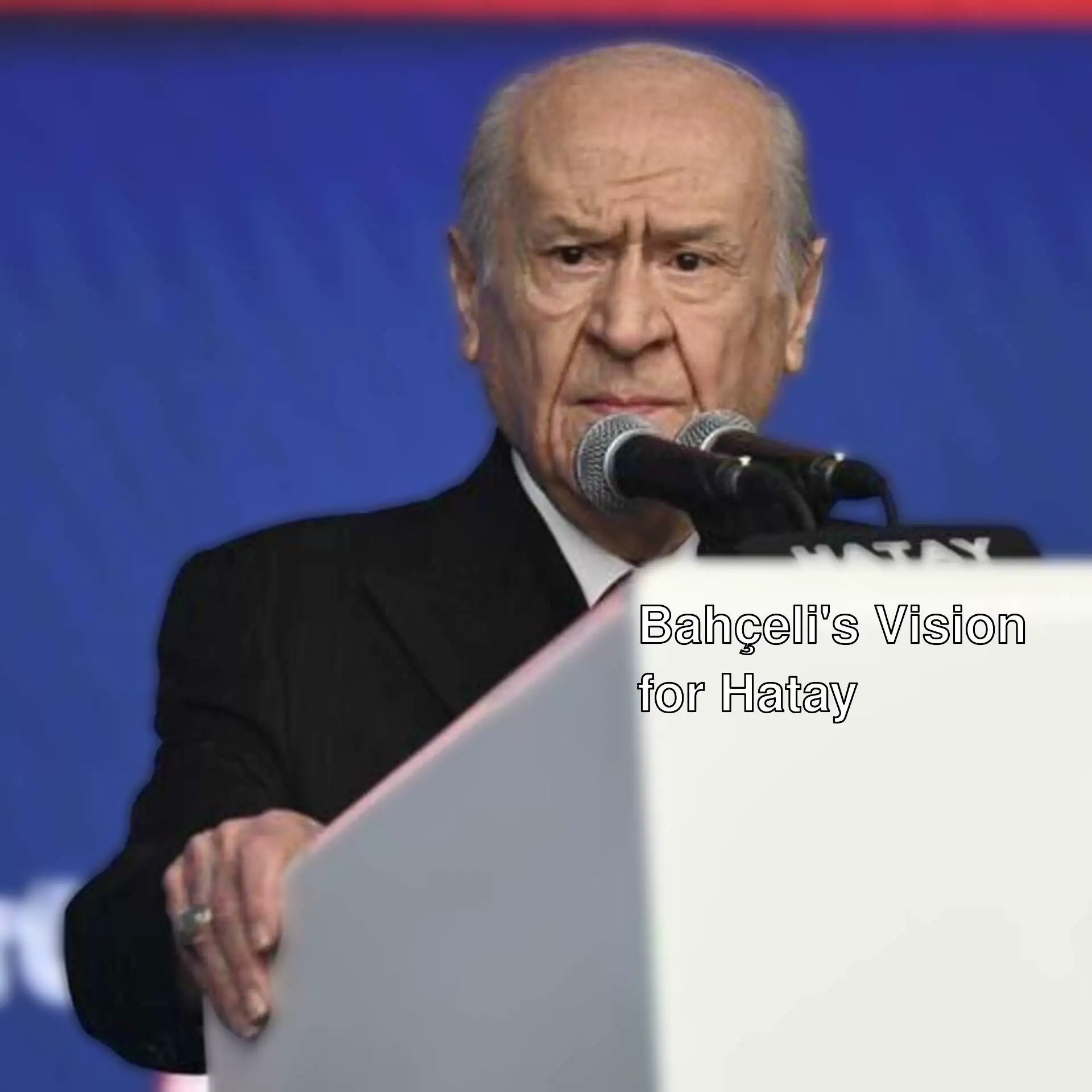 Devlet Bahçeli speaking into a microphone.