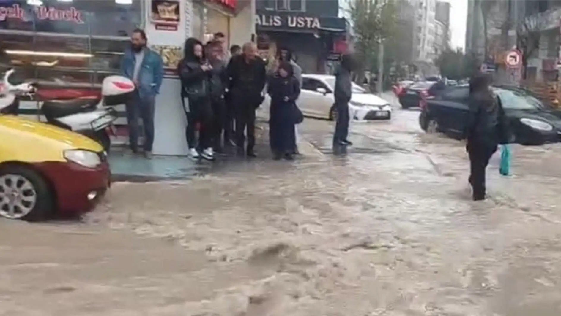 Elazığ'da su baskınları nedeniyle bir grup insan sular altında kalmış bir sokakta duruyor.