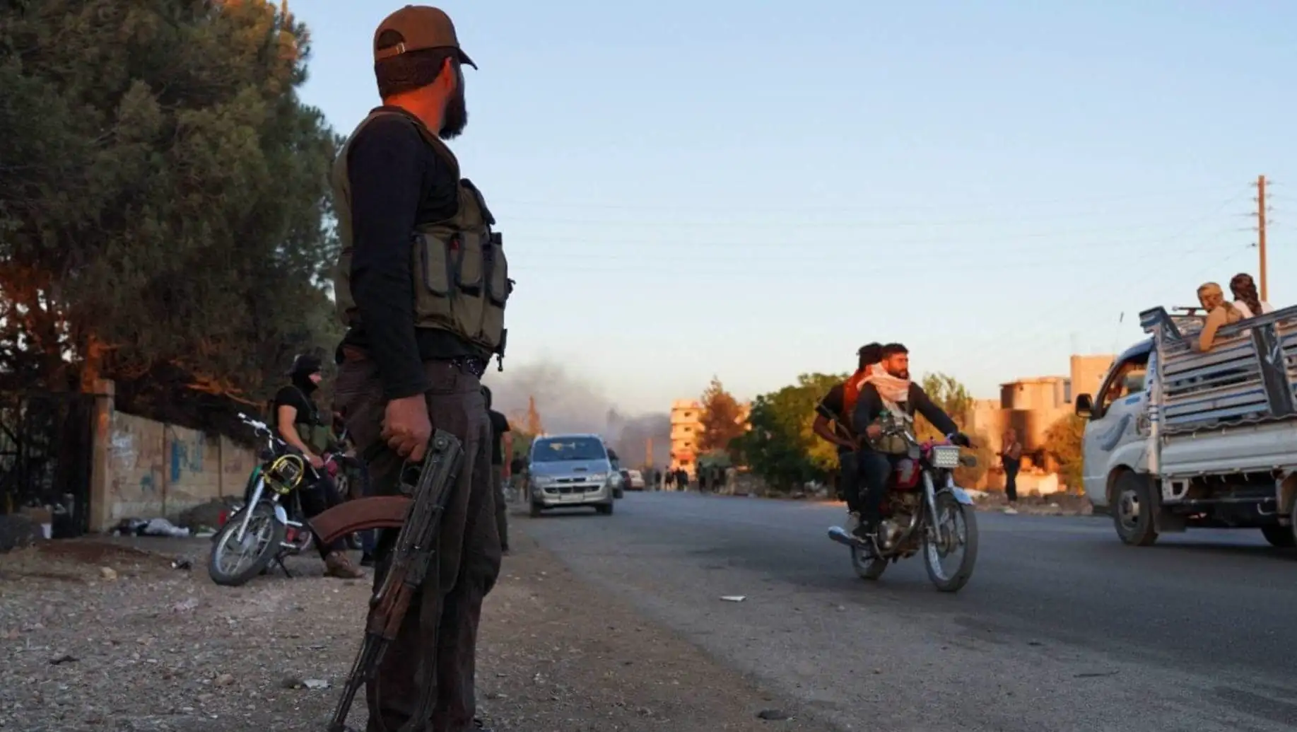 A man holding a gun on a road with other people on motorcycles. A man holding a gun on a road with other people on motorcycles.