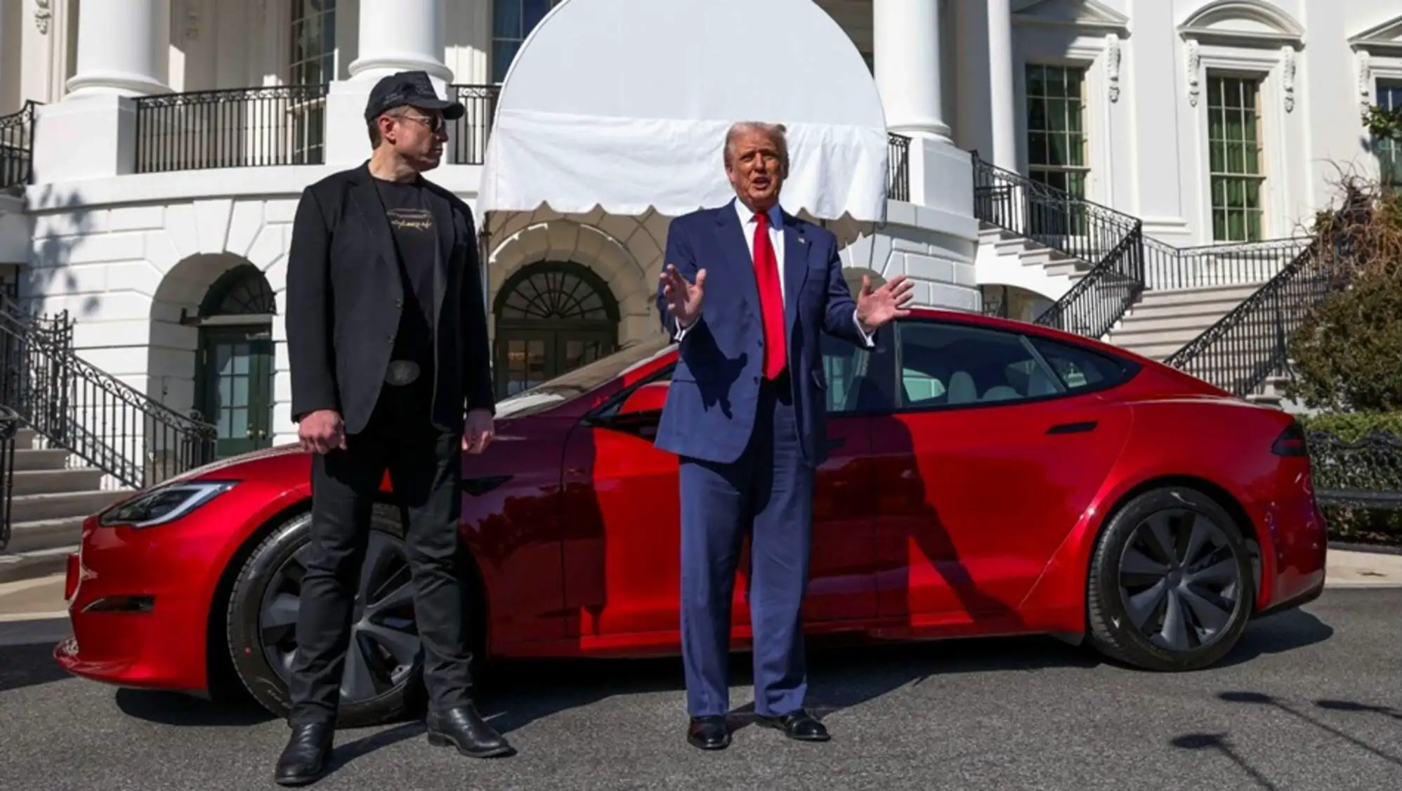 Donald Trump poses with a Tesla vehicle.