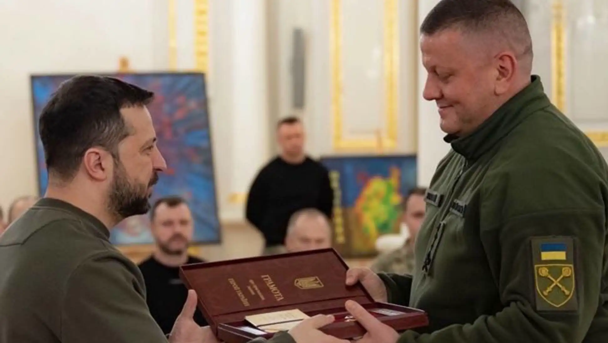 A man holding a box with another man in the background. A man holding a box with another man in the background.