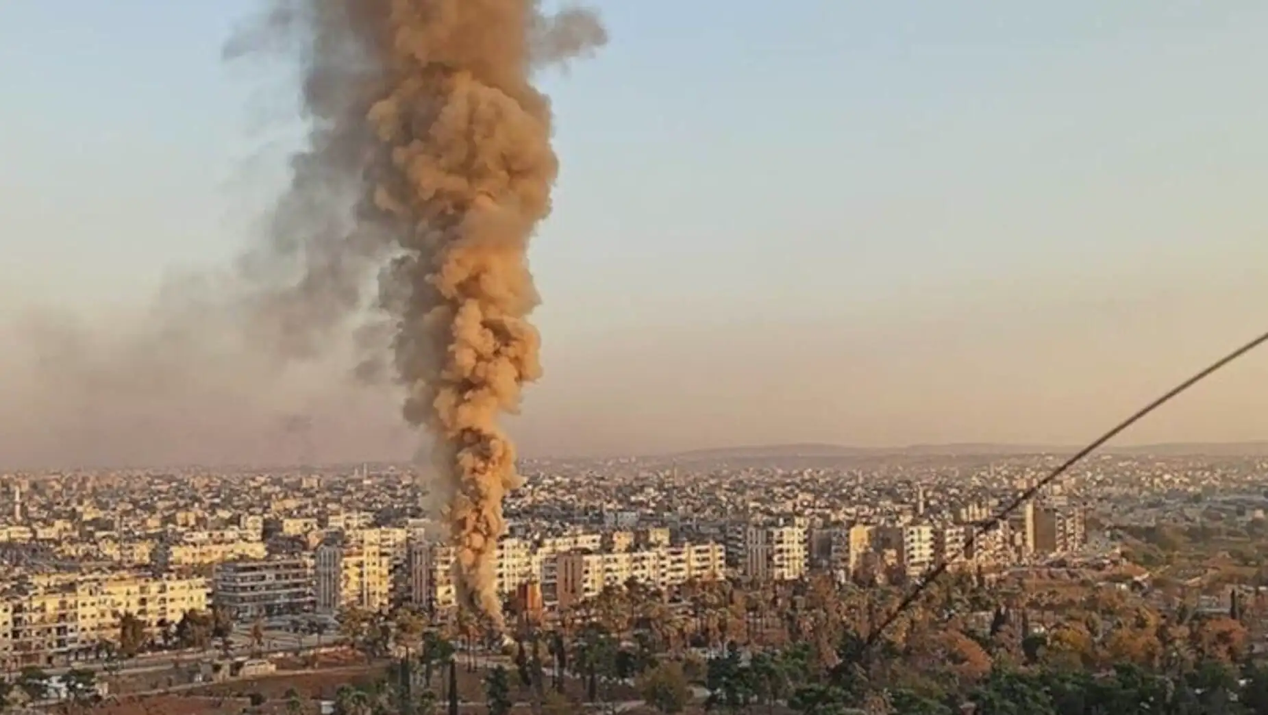 A large plume of smoke in a city A large plume of smoke in a city