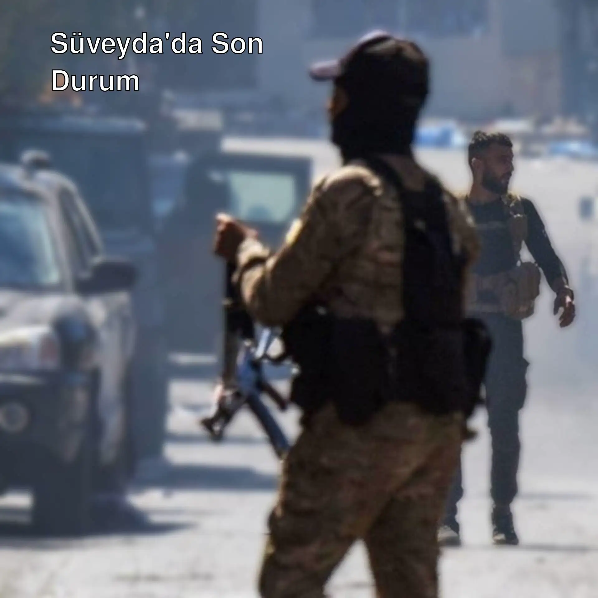 Askeri üniforma giymiş bir adam, bir aracın önünde silah tutuyor.
