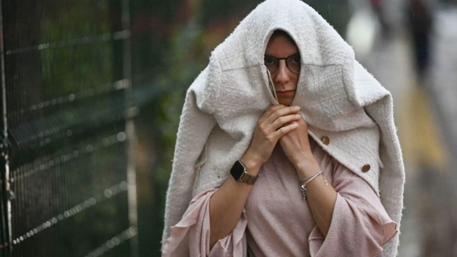 A woman with glasses and a blanket over her head A woman with glasses and a blanket over her head