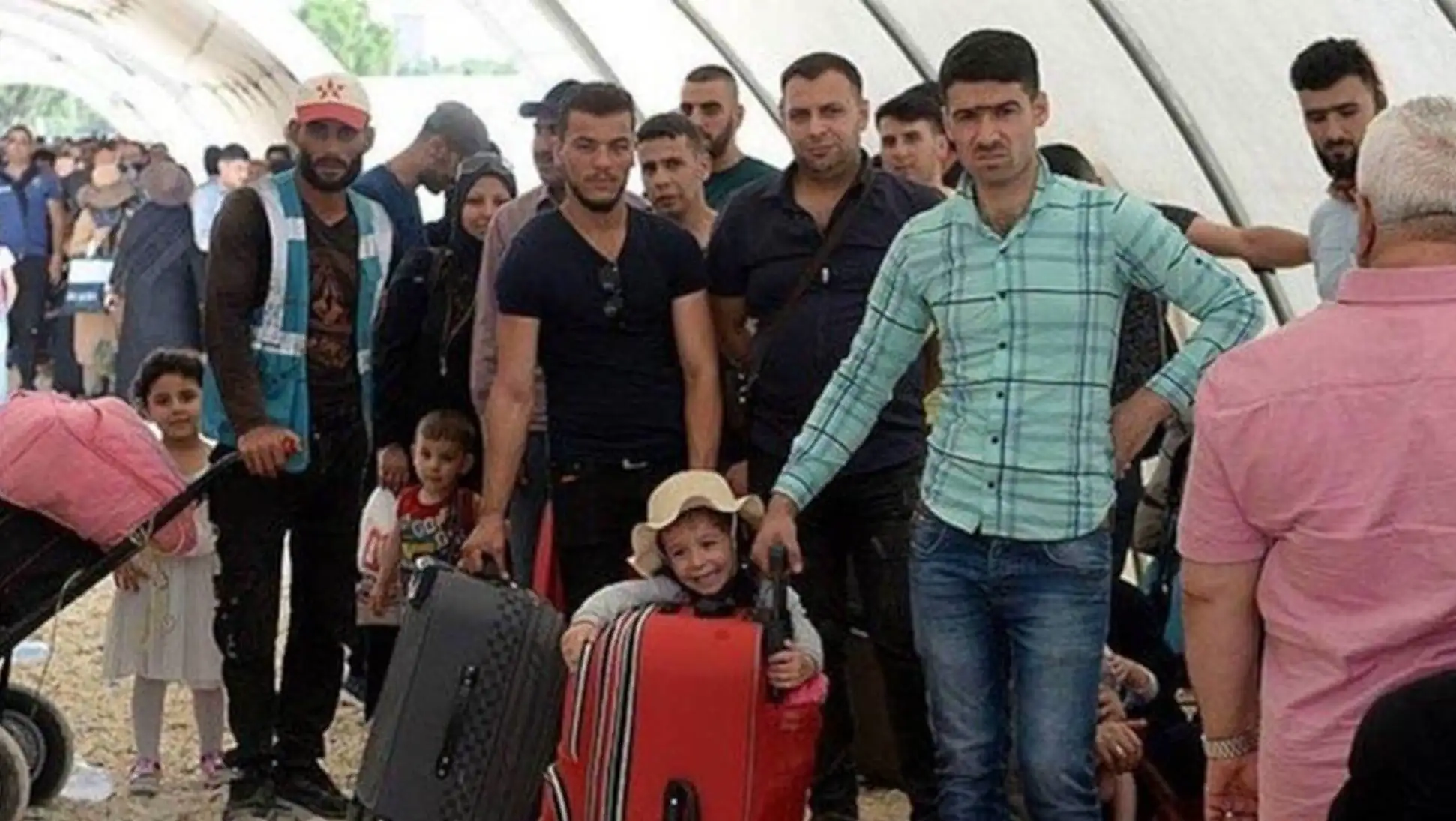 A group of people standing in front of a suitcase. A group of people standing in front of a suitcase.
