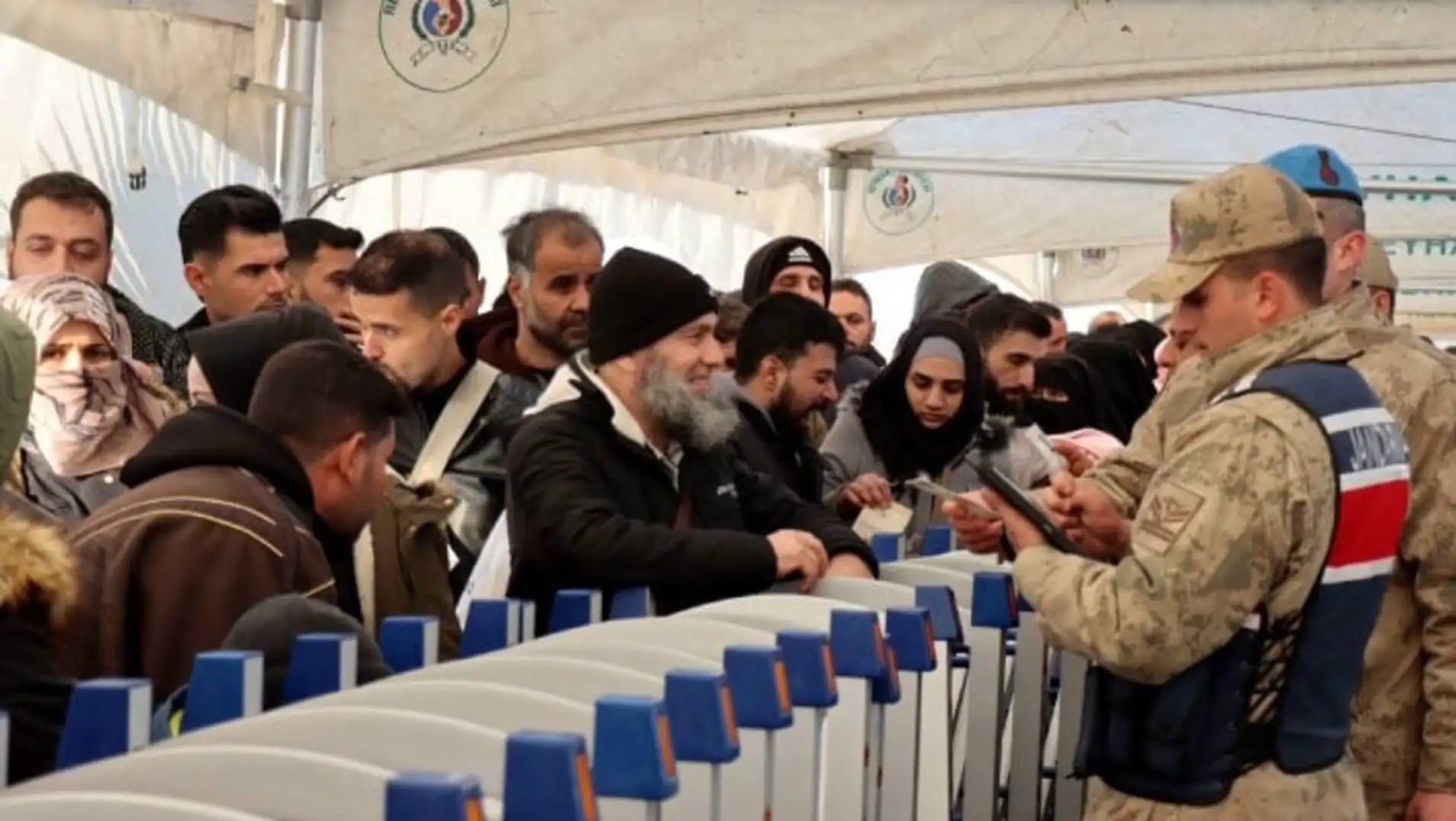 Askeri üniforma giymiş bir adam, insanların önünde duruyor.