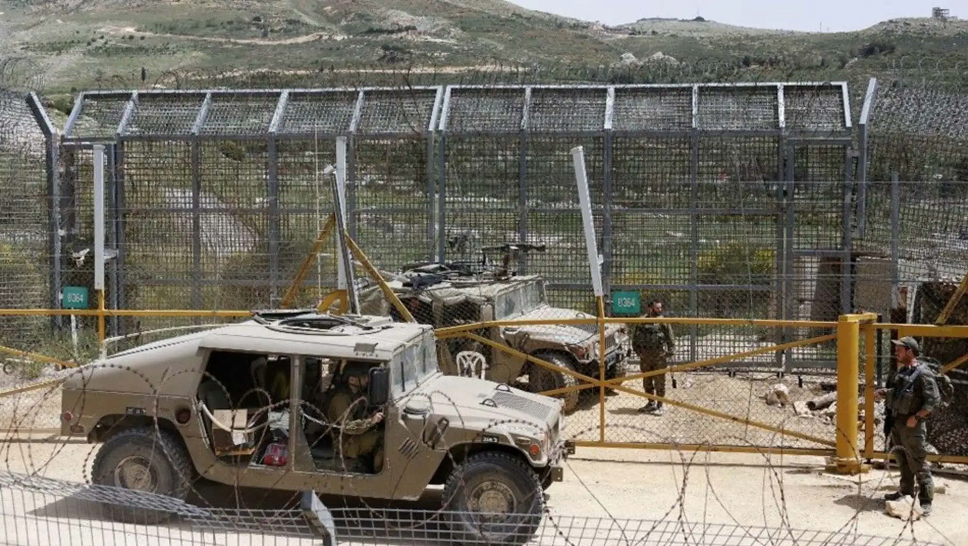 Military vehicles parked in a fenced area.