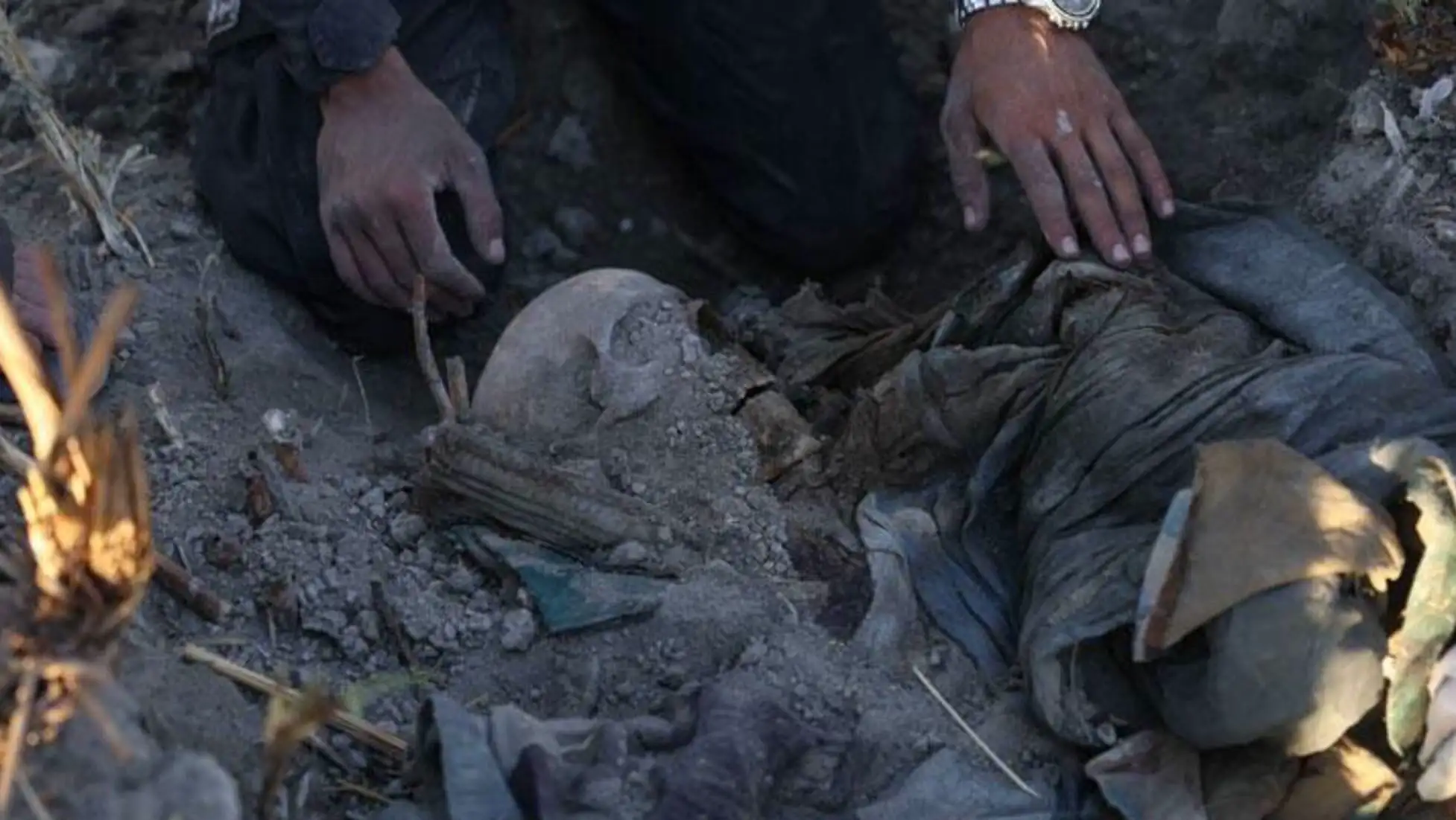 A person touching a skeleton. Efforts continue in Syria's mass grave investigations.