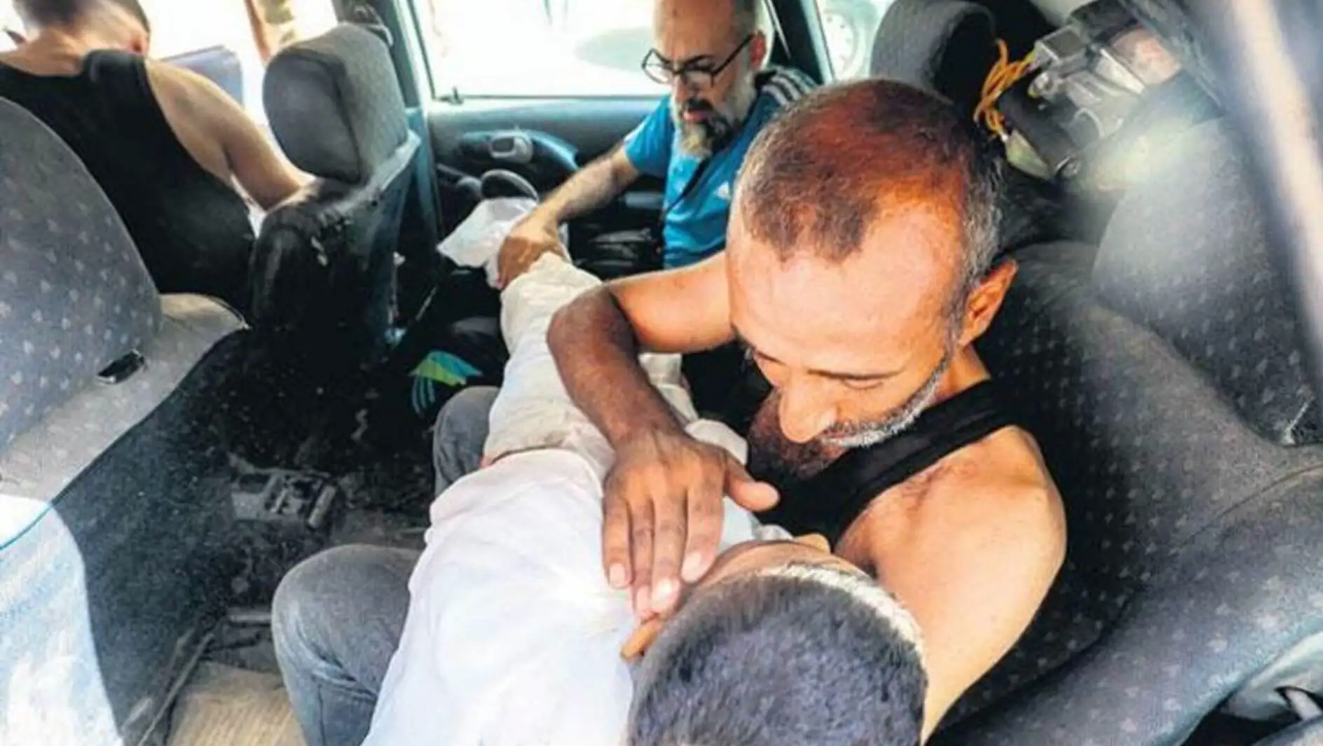 A man holding a person in the back of a car.