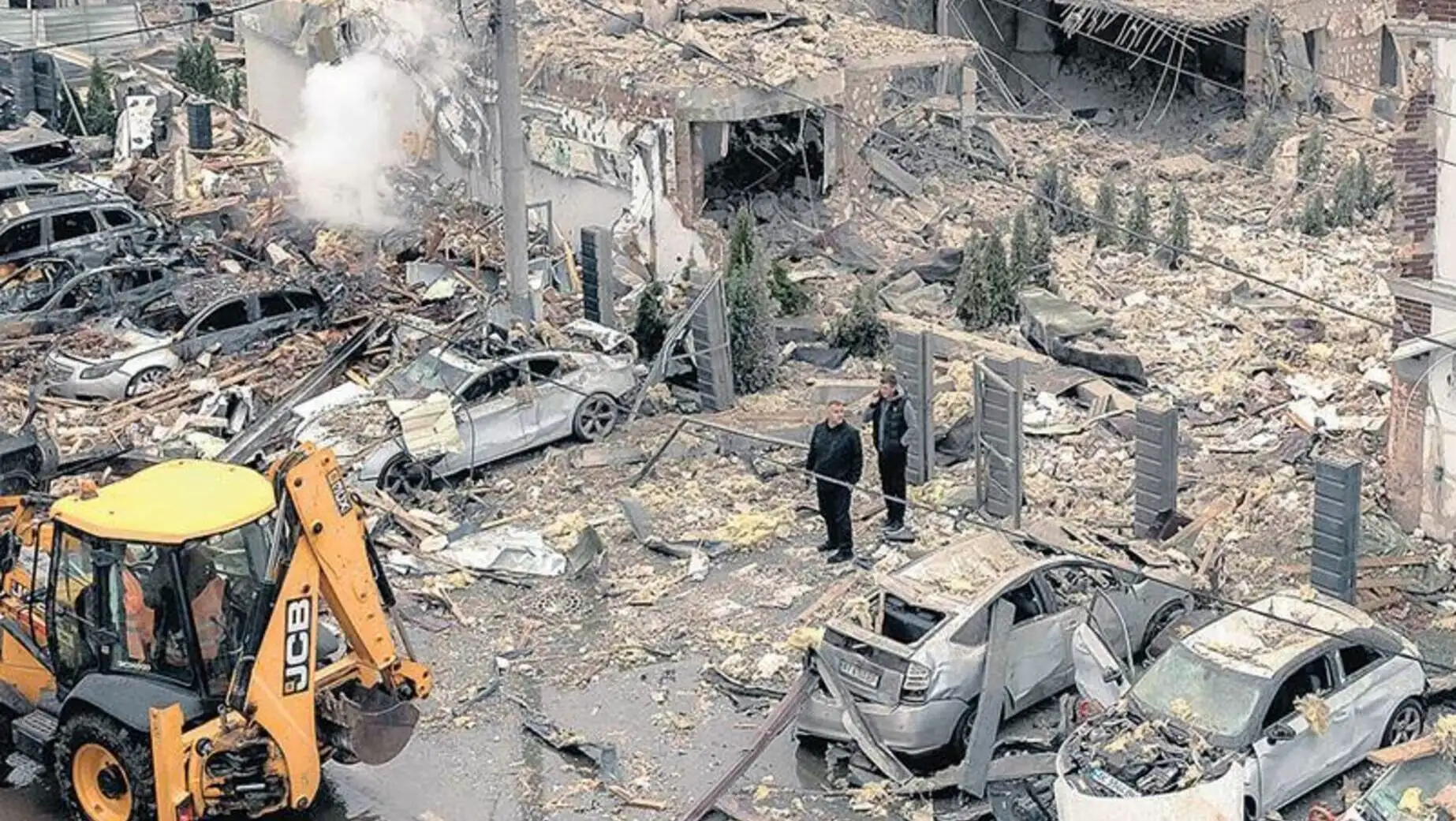 A couple of men standing in front of a destroyed building.