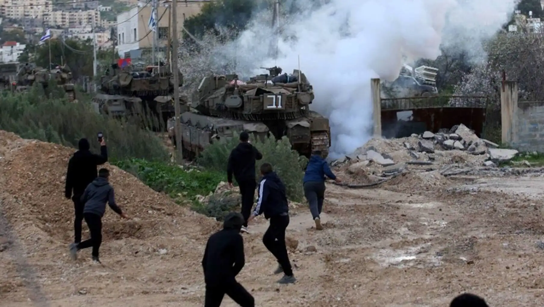A group of people walking past a military tank. A group of people walking past a military tank.