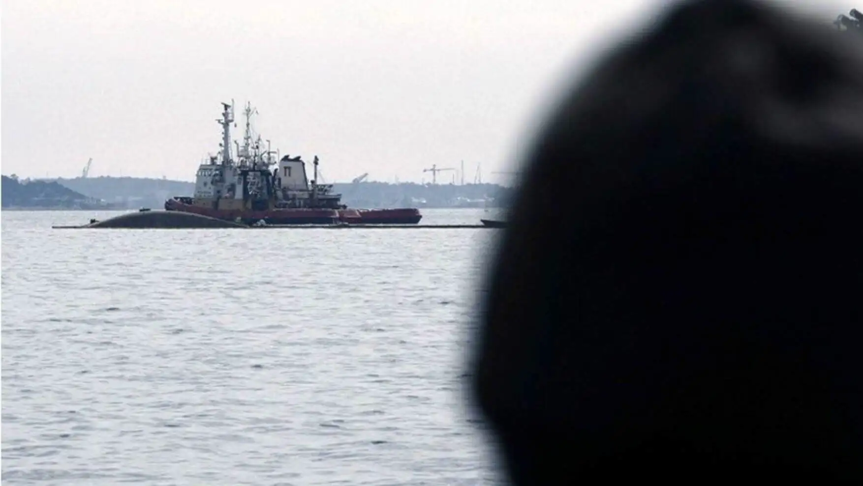 A person looking at a ship in the water. A person looking at a ship in the water.