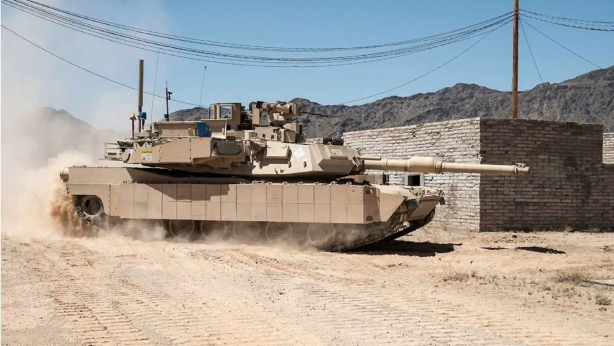 A military tank driving on a dirt road.