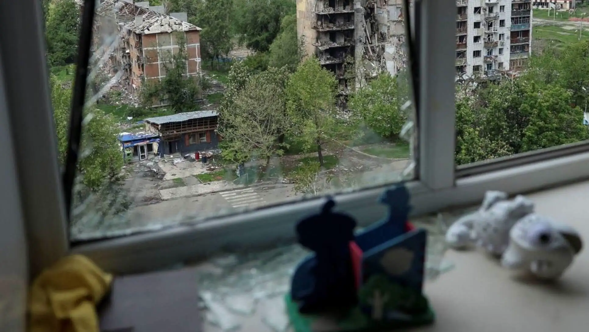 Kırık bir camdan bir pencere ve arka planda binalar.