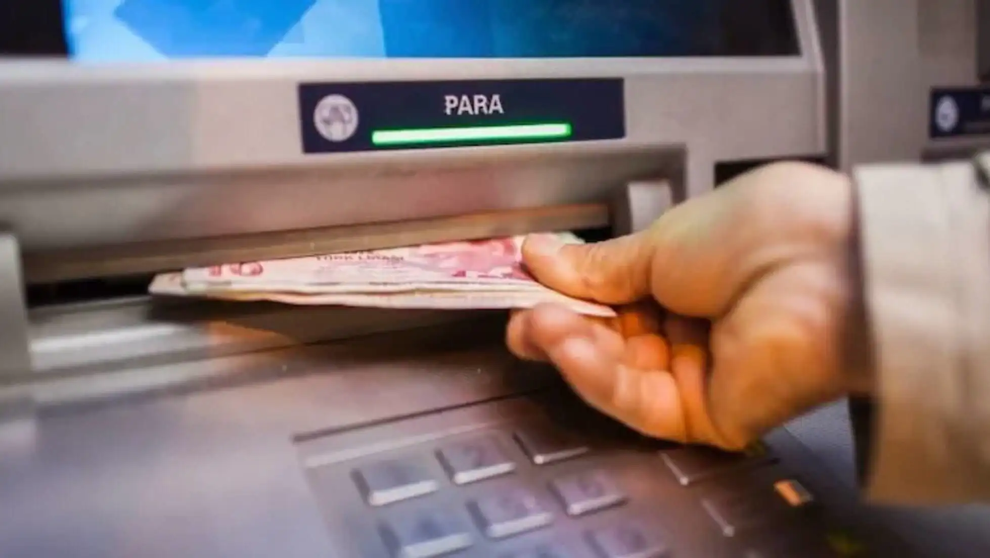 Bir elin ATM'ye para koyduğu görüntü.