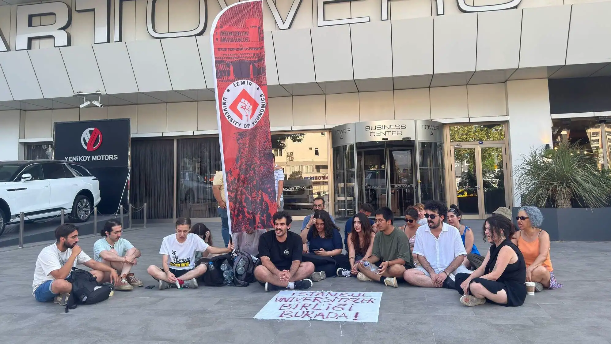 A group of people sitting on the ground outside of a building.