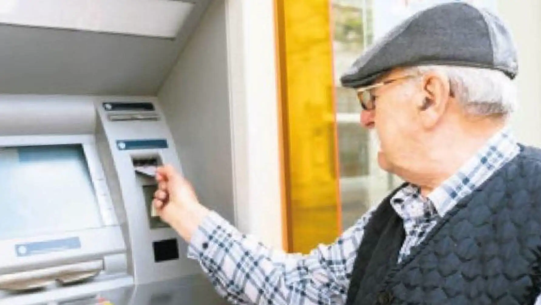 Bir adam ATM'de kredi kartı kullanıyor. Bir adam ATM'de kredi kartı kullanıyor.