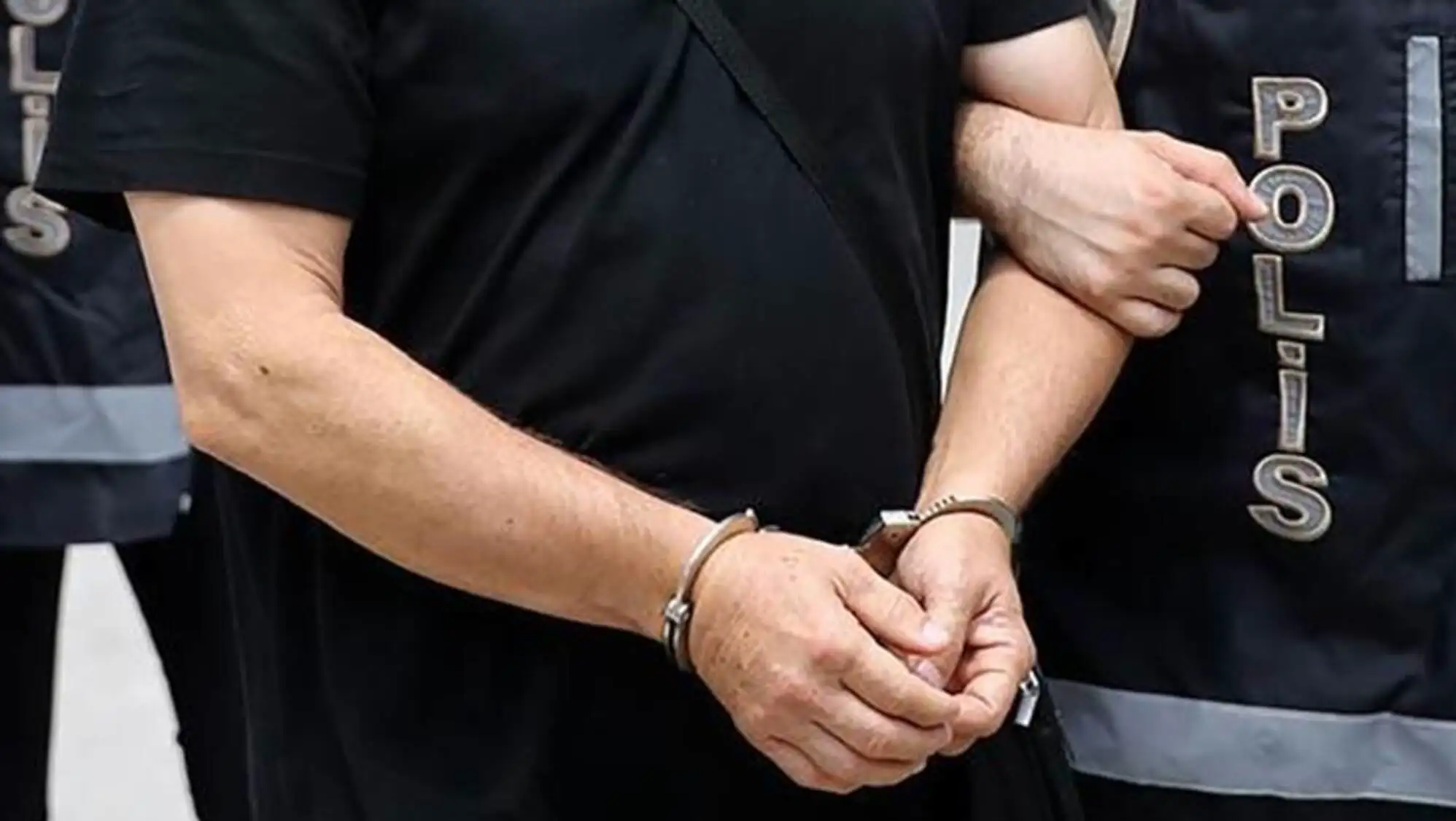 A person in handcuffs with another individual.
