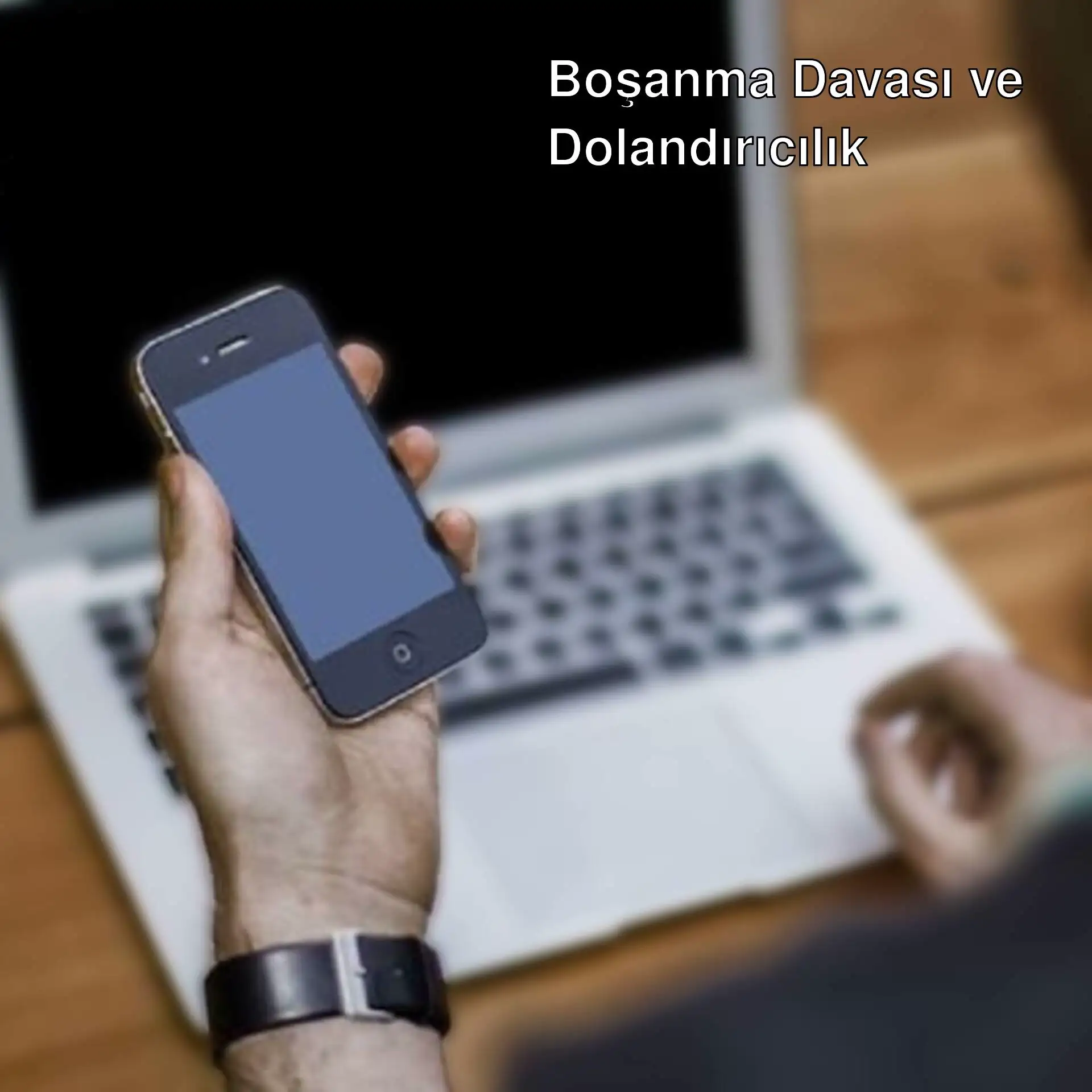 Bir kişi telefon tutarak bilgisayarın önünde duruyor. Bir kişi telefon tutarak bilgisayarın önünde duruyor.