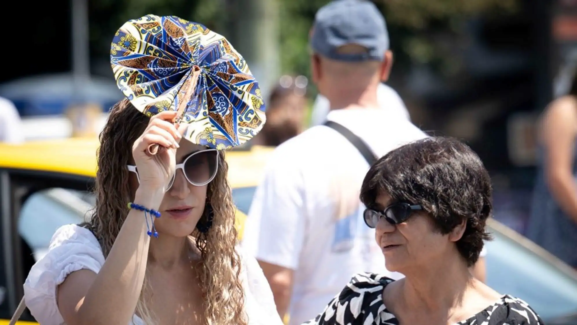 A woman holding a fan over her face.