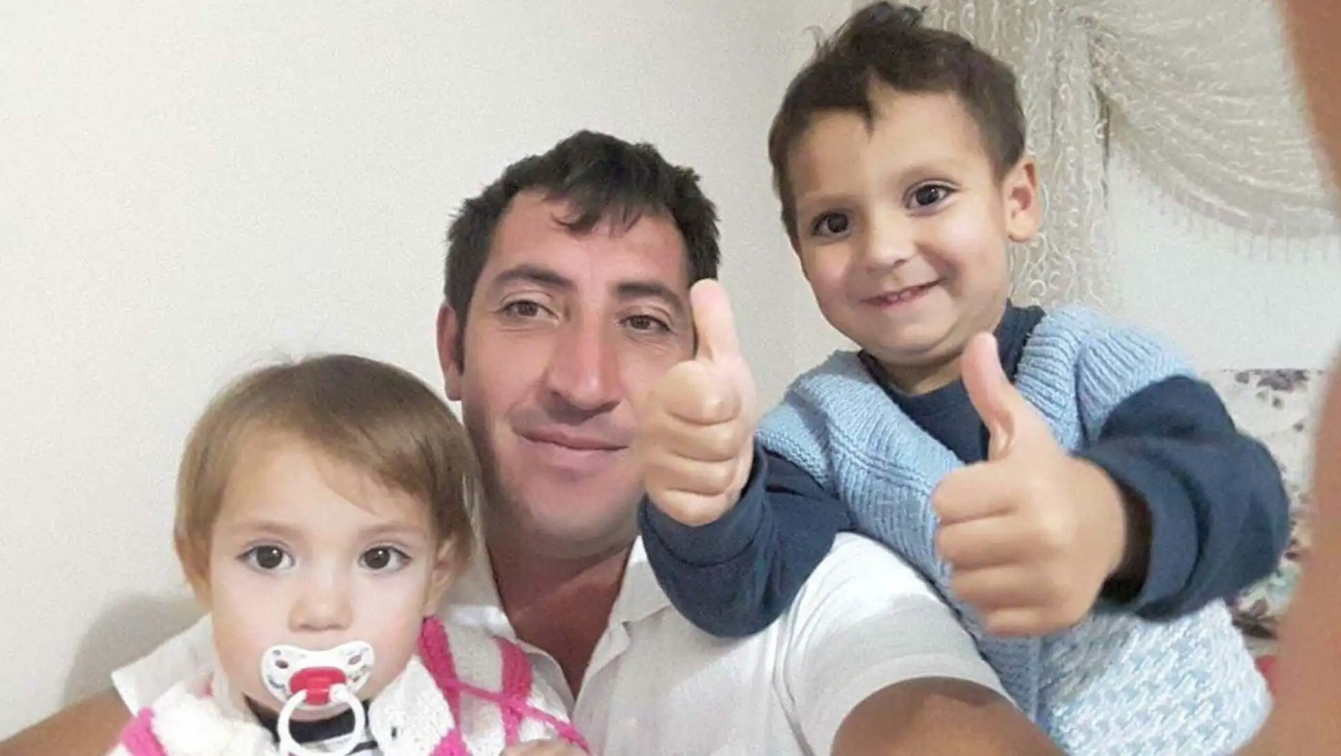 Bir adam iki çocuğu tutuyor. Bir adam iki çocuğu tutuyor.