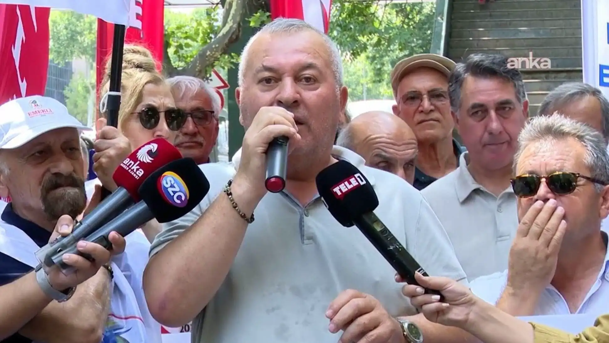Bir adam mikrofonlara konuşuyor.