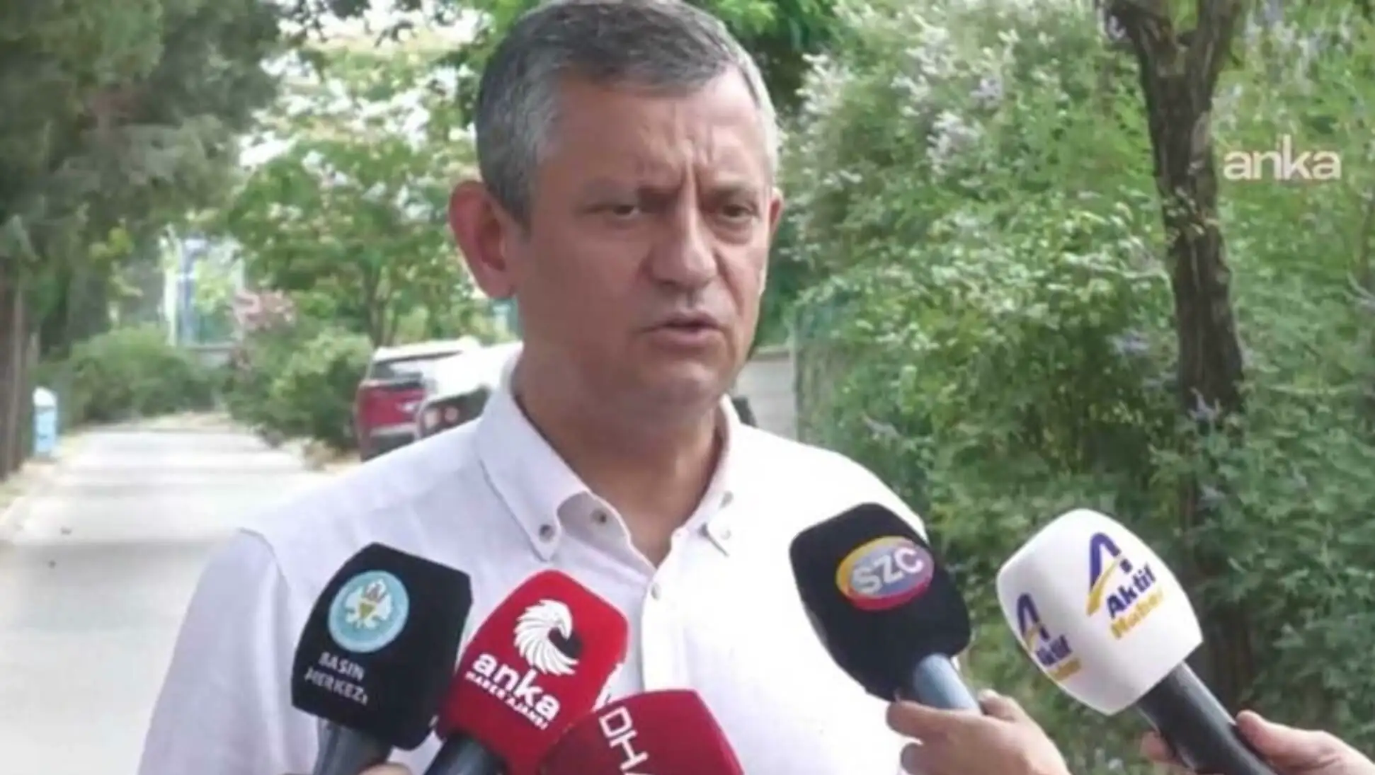 Özgür Özel holding a microphone.