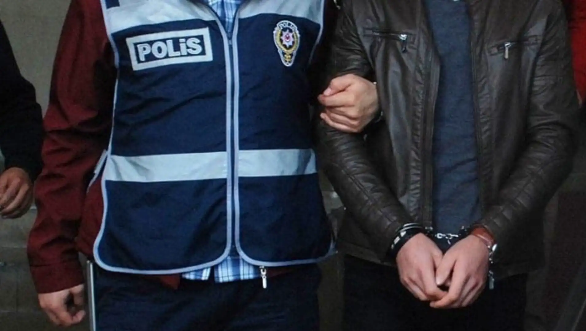 Kelepçeli bir adam, polis ceketi tutuyor. Kelepçeli bir adam, polis ceketi tutuyor.