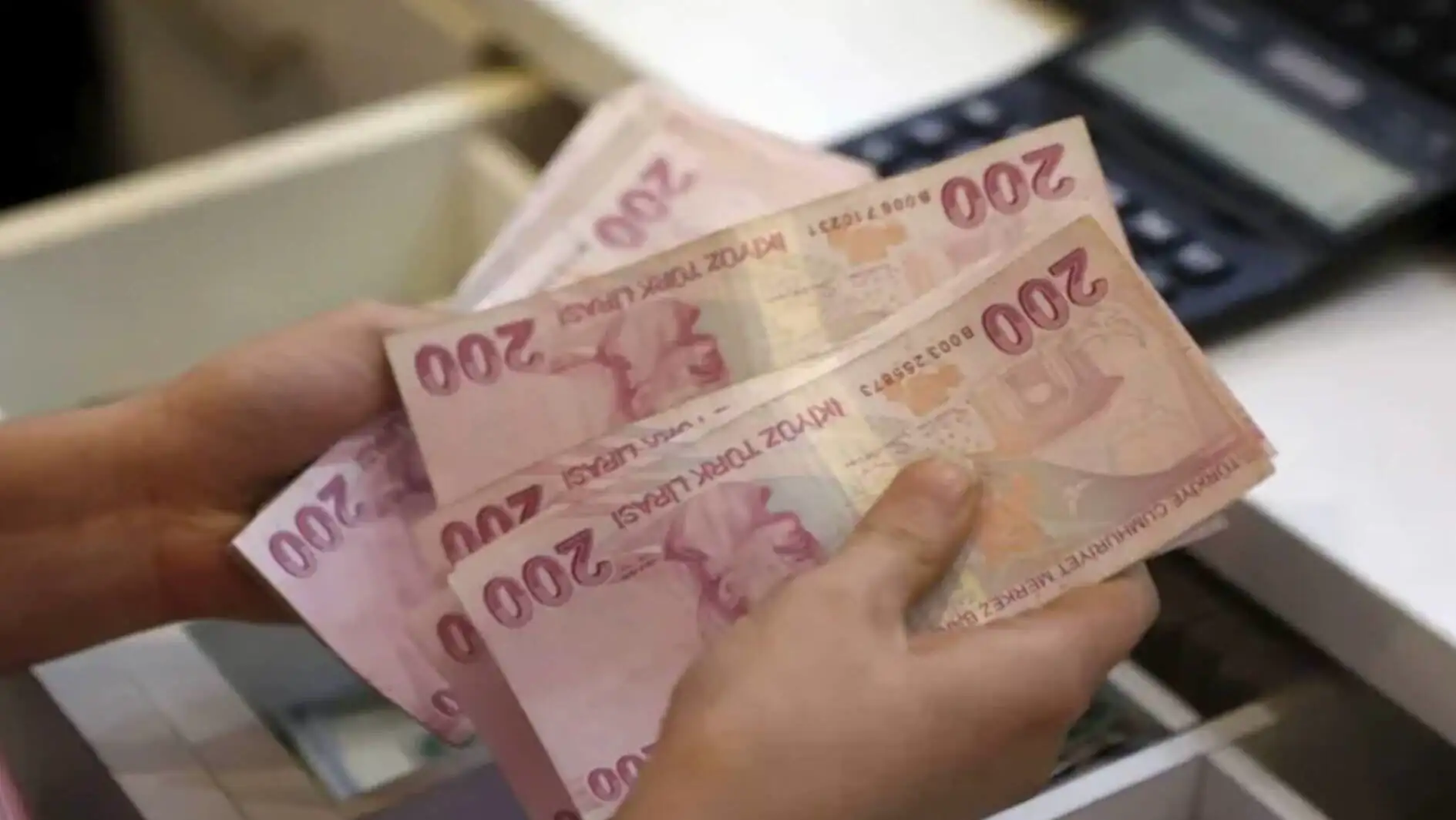 A person holding money. As pension salaries fall, bread prices rise.
