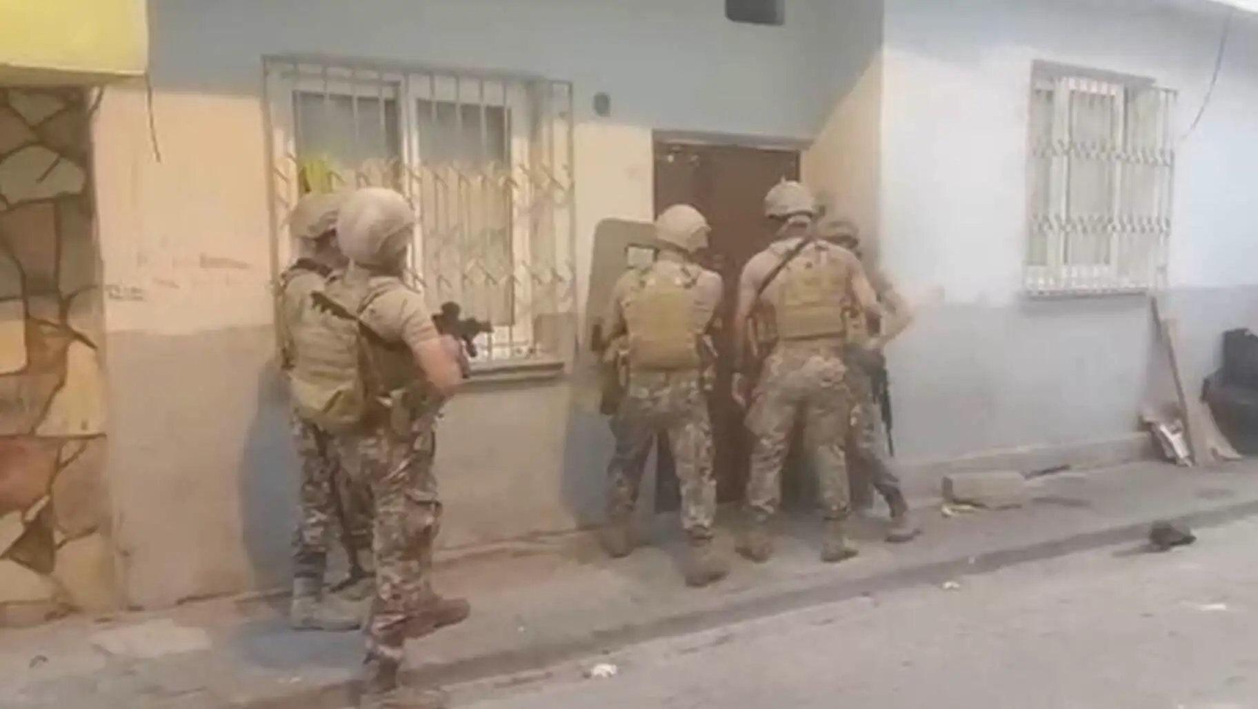 A group of soldiers standing on the side of a street. A group of soldiers standing on the side of a street.