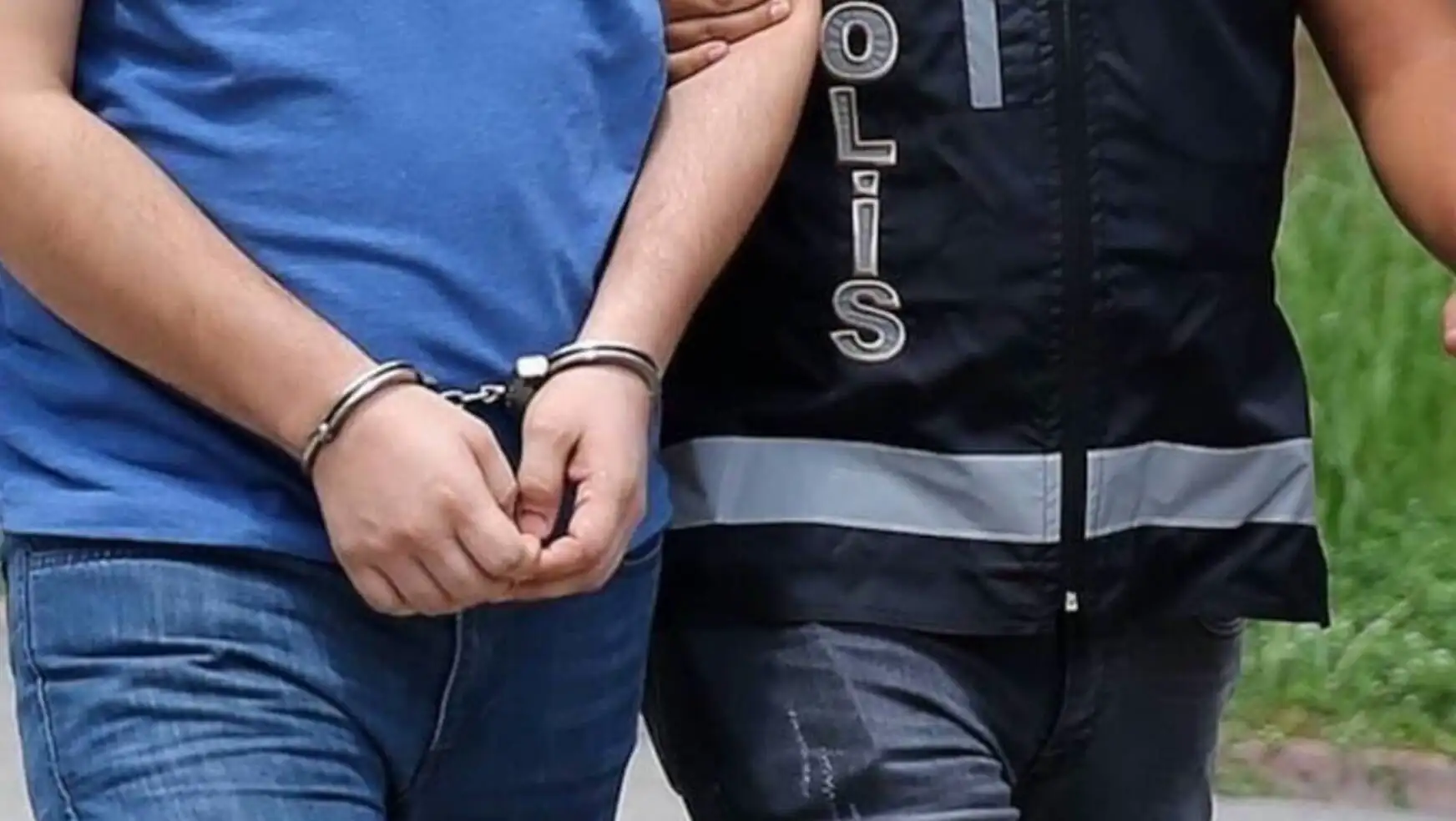 Gözaltına alınan bir kişi ve arka planda bir polis memuru.