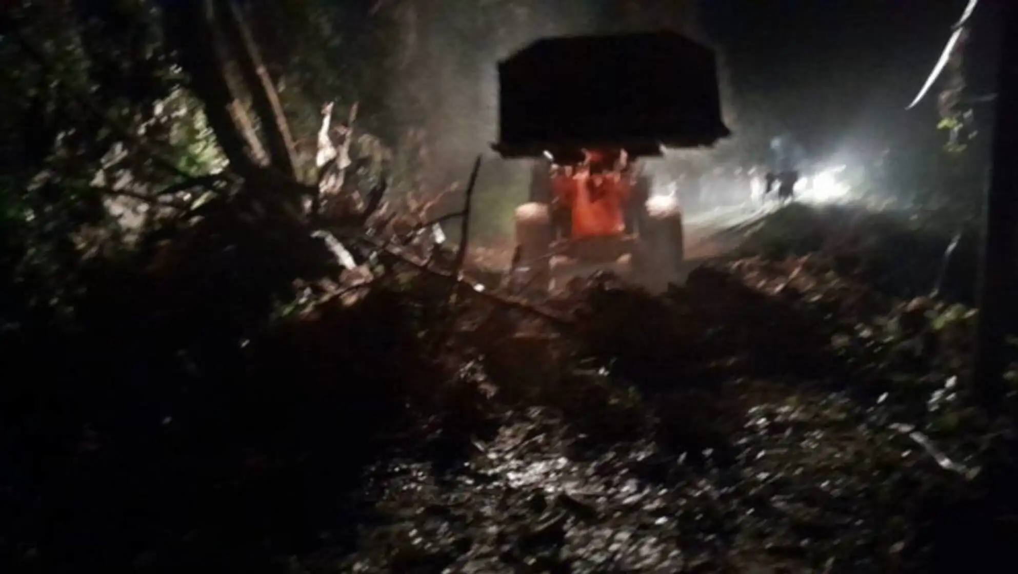 A tractor on a muddy road at night.