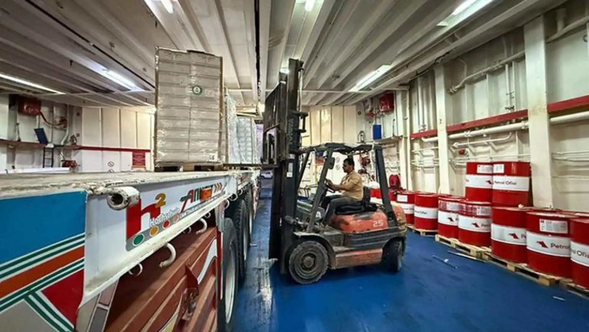 A man driving a forklift in a warehouse. A man driving a forklift in a warehouse.