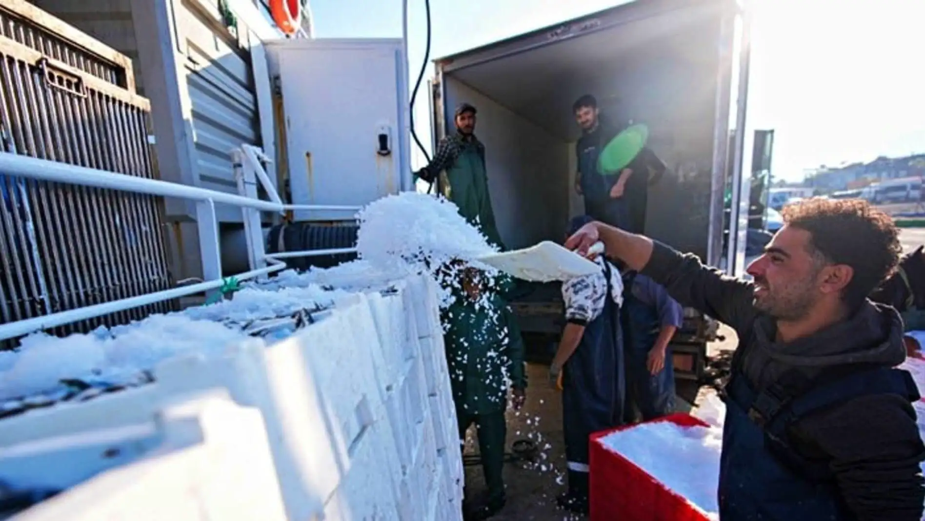 A group of men pouring snow on a truck. A group of men pouring snow on a truck.