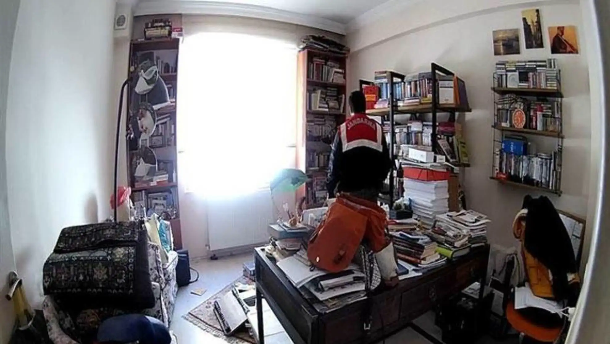 A man standing on a desk in a room with a large window.