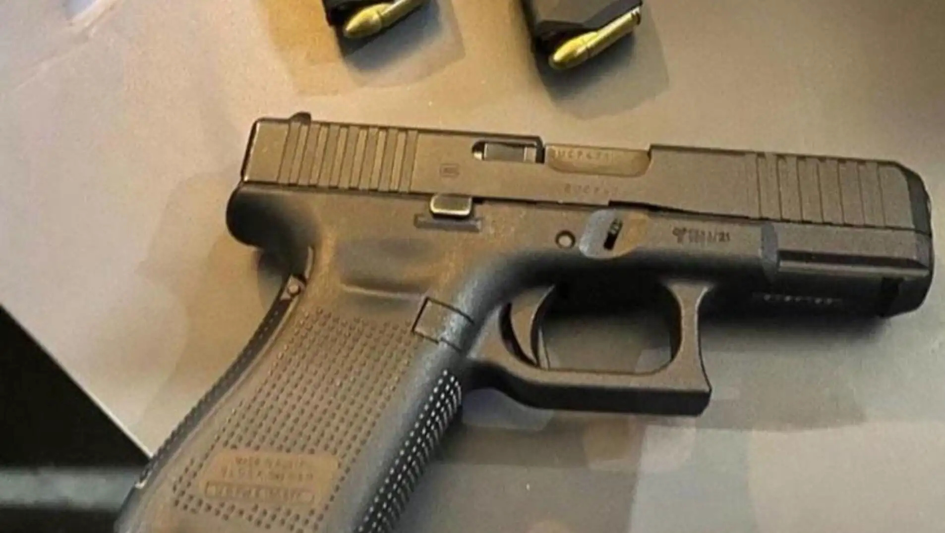 A black gun with bullets on a table.