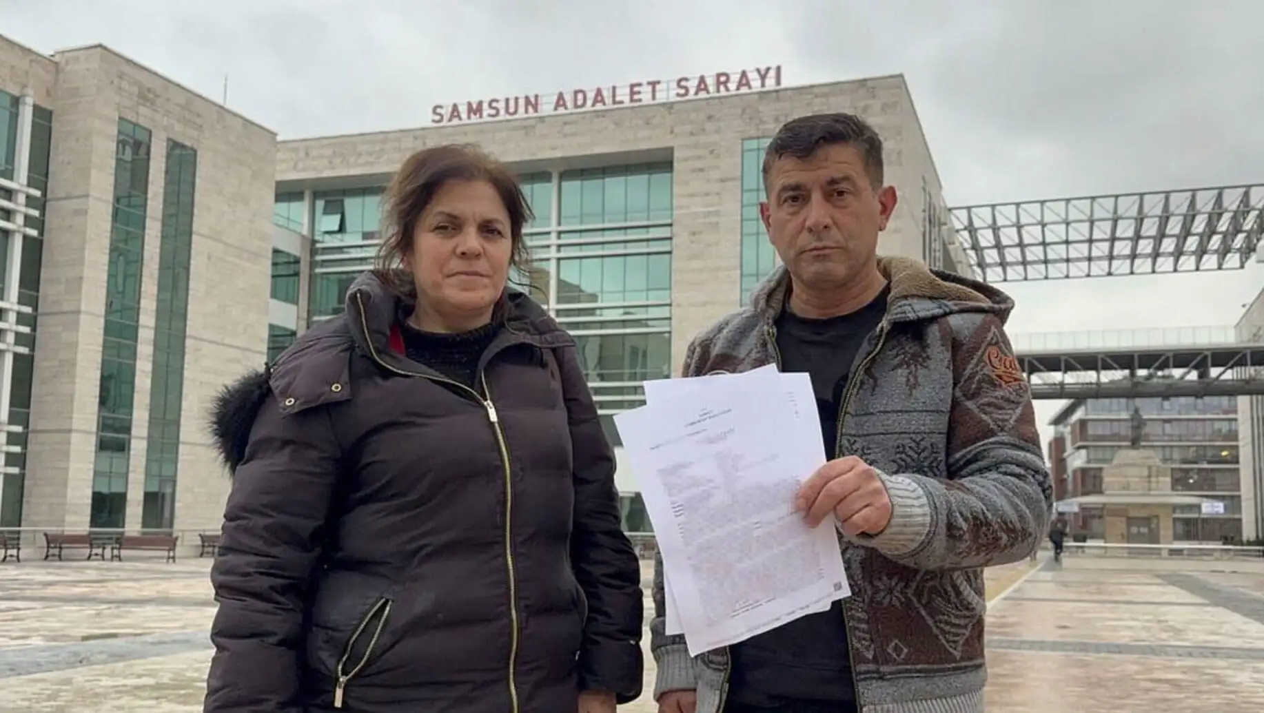 A man and woman holding papers in front of a building. A man and woman holding papers in front of a building.