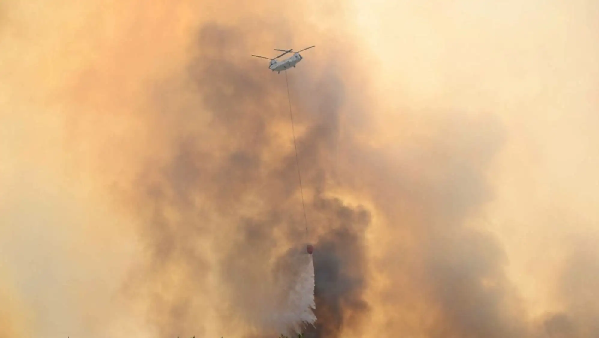 A helicopter dropping water on a forest fire